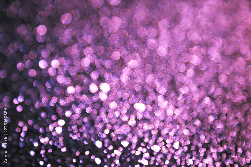 Abstract background with bokeh blurred lights. Shimmering bright red, purple, violet sequins on a dark background. The picture creates and accentuate a festive magical mood. New year, Christmas.