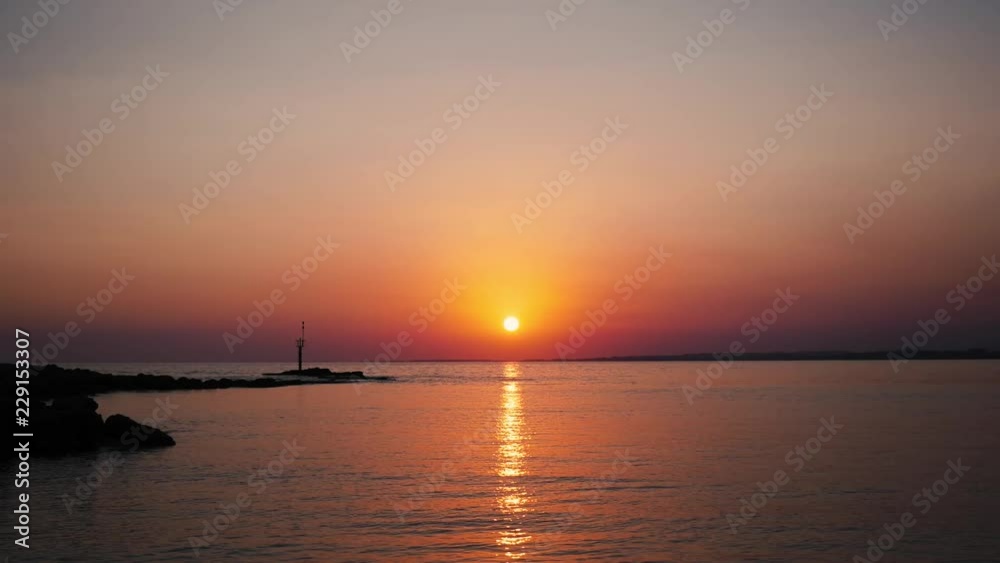 Timelapse of beautiful warm red sunset with sun rays reflected in calm ocean water Timelapse of beautiful warm red sunset with sun rays reflected in calm ocean water