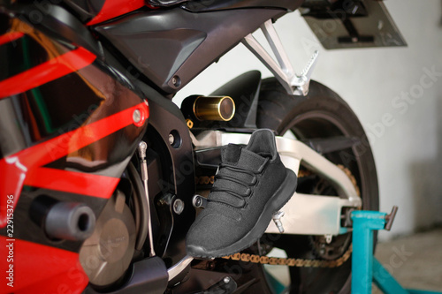 Black sports shoes on a red sports bike
