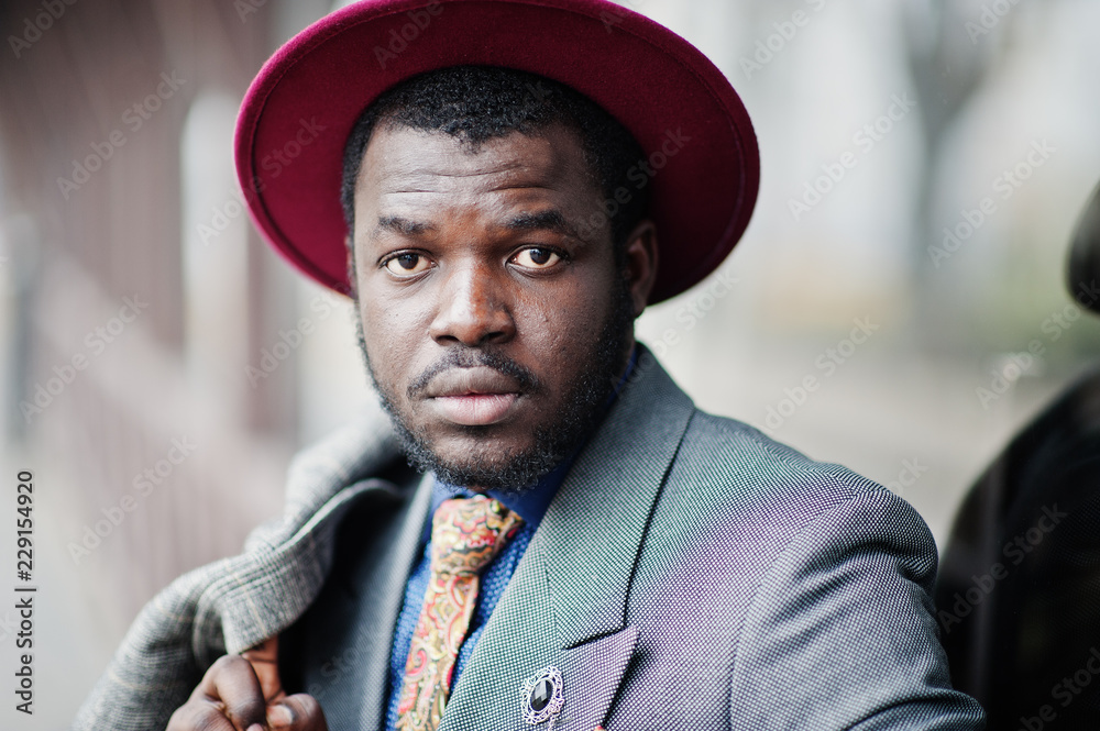 Close up portrait of stylish African American man model in gray coat, jacket tie and red hat. Close up portrait of stylish African American man model in gray coat, jacket tie and red hat.