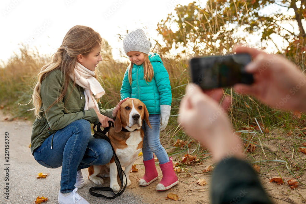 family, leisure and people concept - happy mother, father and little daughter photographing by smartphone on autumn beach family, leisure and people concept - happy mother, father and little daughter photographing by smartphone on autumn beach