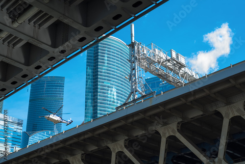 Urban environment, bridge structure, office buildings, flying helicopter  photo