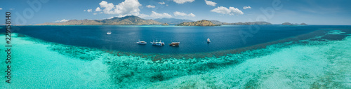 Aerial drone panoramic shot ocean, Komodo background. Transparent turquoise water of the Pacific ocean with the boats taken for tourist reasons. Komodo National Park, Indonesia. © Goinyk