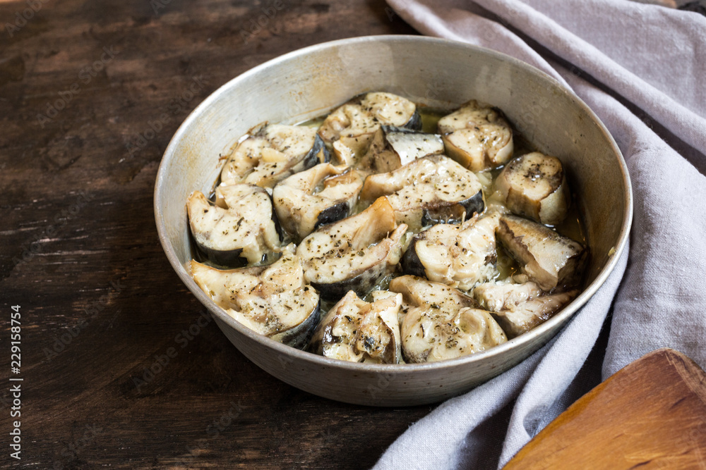 Baked fish mackerel in a pan, on a wooden background. Slices of baked Atlantic mackerel Baked fish mackerel in a pan, on a wooden background. Slices of baked Atlantic mackerel