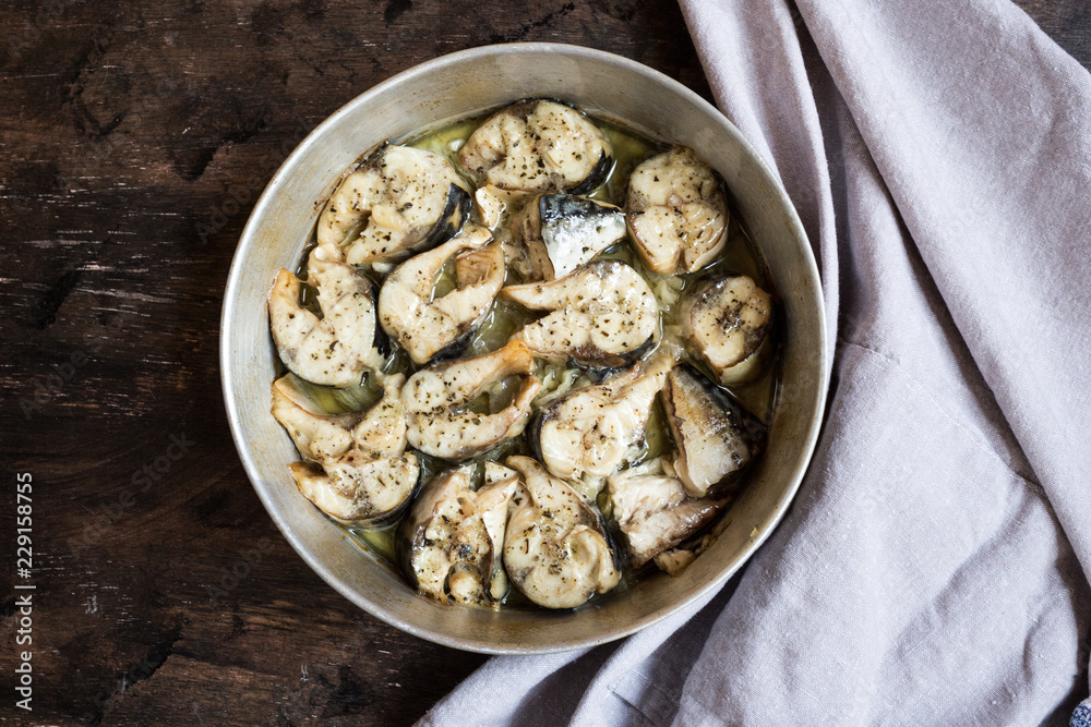 Baked fish mackerel in a pan, on a wooden background. Slices of baked Atlantic mackerel Baked fish mackerel in a pan, on a wooden background. Slices of baked Atlantic mackerel