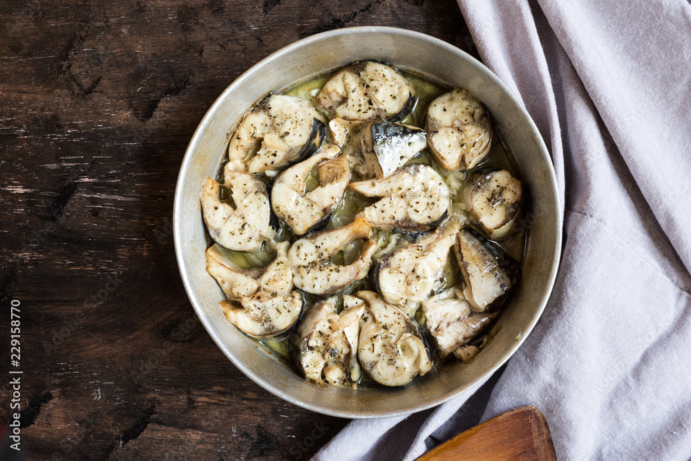 Baked fish mackerel in a pan, on a wooden background. Slices of baked Atlantic mackerel Baked fish mackerel in a pan, on a wooden background. Slices of baked Atlantic mackerel