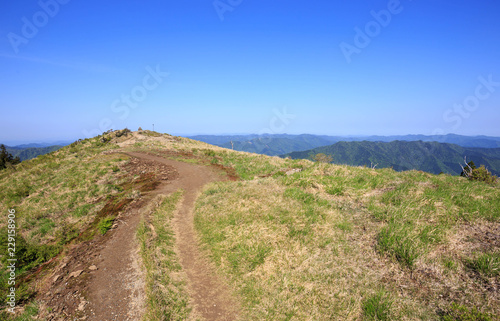 Dirt trail to top of mountain under vibrant blue sky on sunny day