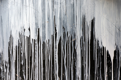 Drips of white paint on black wall.