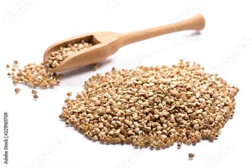 Close-up of pile of green buckwheat in a wooden spoon on white background