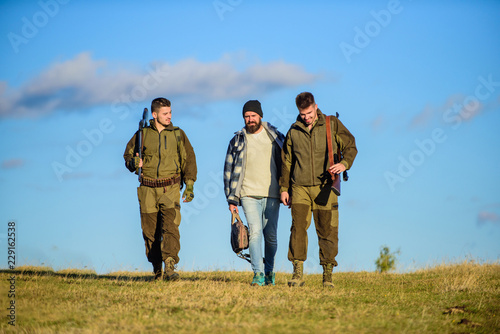 Brutal hobby. Group men hunters or gamekeepers nature background blue sky. Men carry hunting rifles. Hunting as hobby and leisure. Hunters with guns walk sunny fall day. Guys gathered for hunting