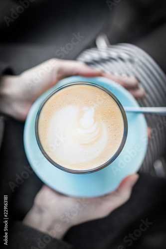 Female hands holding a cup of coffee latte on a black and white background
