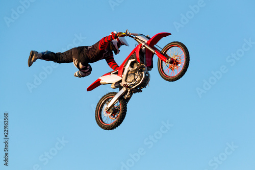 Freestyle motocross biker performs the trick in jump at fmx competitions