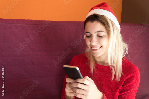 pretty young girl at home with mobile phone at christmas photo
