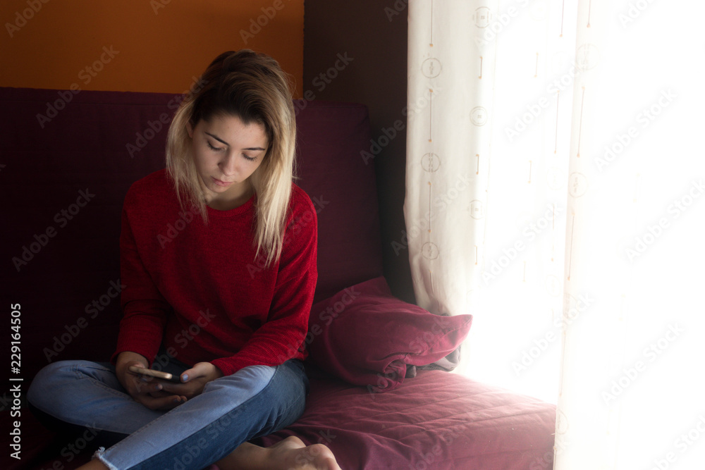 Fototapeta premium pretty young girl at home with mobile phone