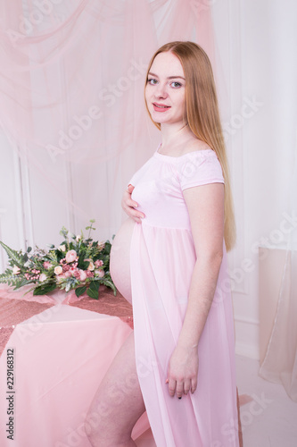 Pregnant woman in pink dress. Motherhood, pregnancy
