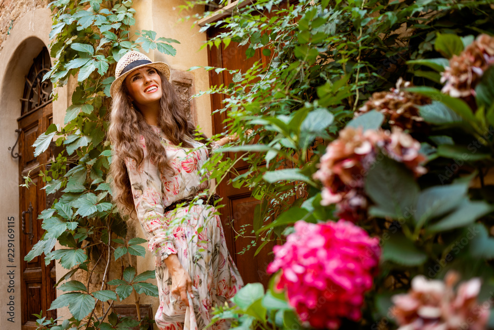 happy tourist woman in Pienza, Italy standing amount flowers