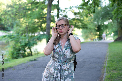 Young woman in headphones listening to music on the street in summer