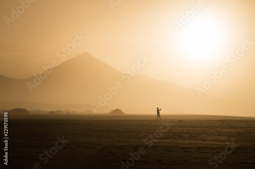 Silhouette of man walking on Cofete beach at sundown in Fuerteventura.