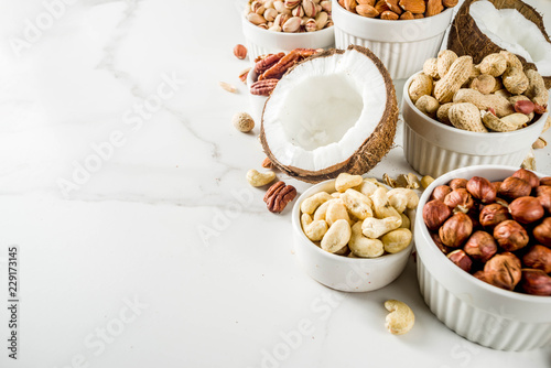 Various types of nuts - walnuts, pecans, peanuts, hazelnuts, coconut, almonds, cashews, in bowls