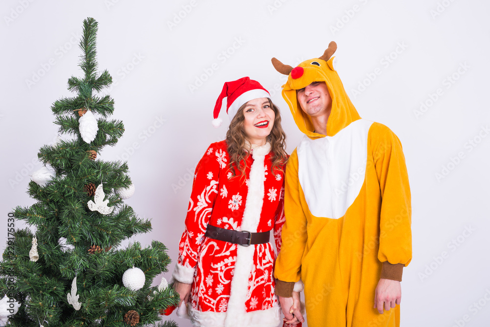 Holiday, Christmas and family concept - Beautiful couple in carnival costumes standing near Christmas tree Holiday, Christmas and family concept - Beautiful couple in carnival costumes standing near Christmas tree