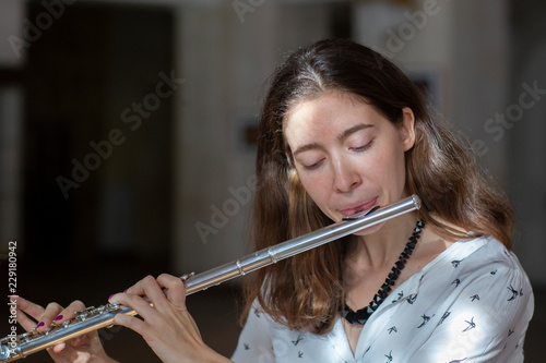 A beautiful woman posing while playing on a flute