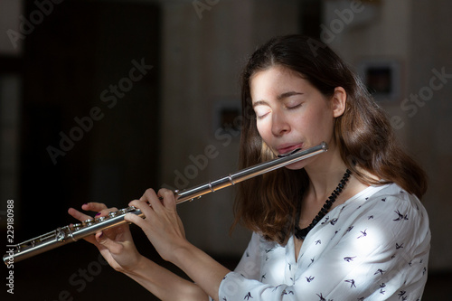 A beautiful woman posing while playing on a flute