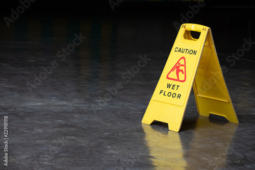 wet floor sign on cement ground. yellow plastic warning sign.