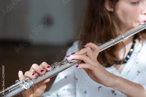 Girl plays on flute. Flute in hands of girl during the concert. Professional musician playing on flute