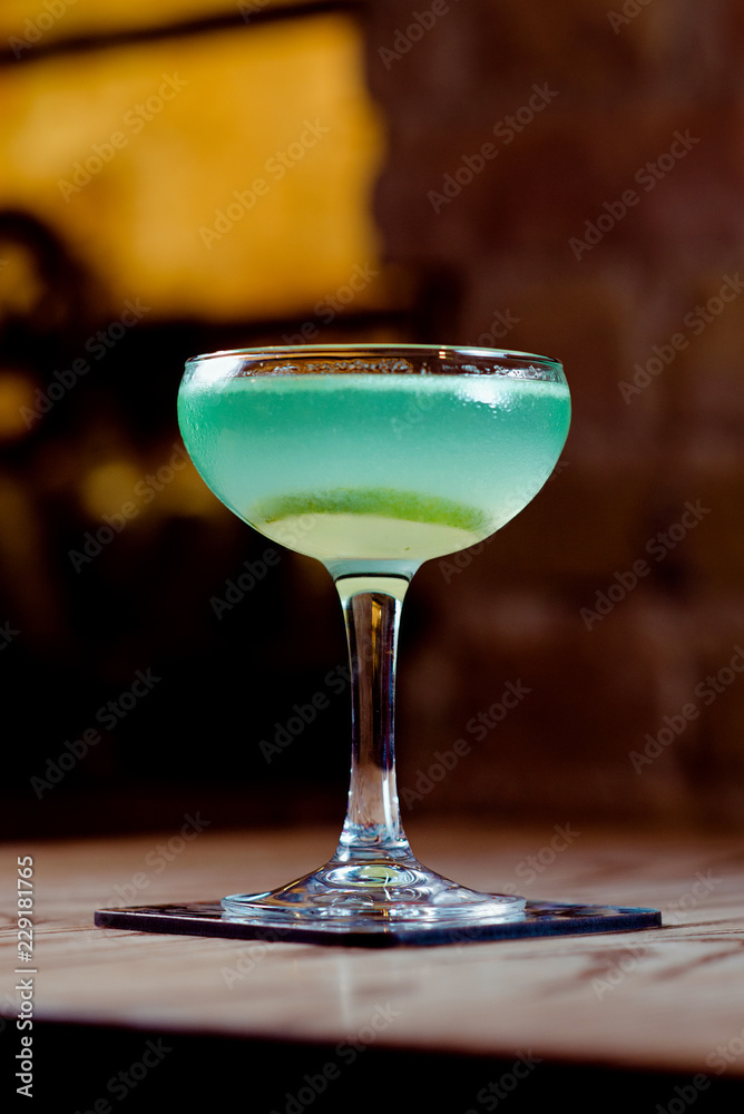 green and blue with lime alcohol cocktail in the glass on the table in bar green and blue with lime alcohol cocktail in the glass on the table in bar