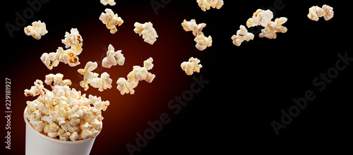 Popcorn flying out of cardboard box. Isolated on black background