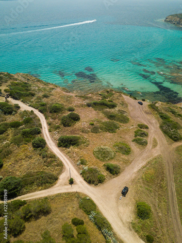 car and crossroad. Beach landscape. Emerald green sea water and rocks on coast of Sardinia, Italy.