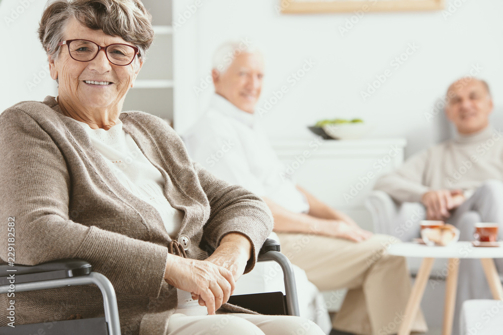 Obraz premium Happy paralyzed senior woman on wheelchair in the nursing house