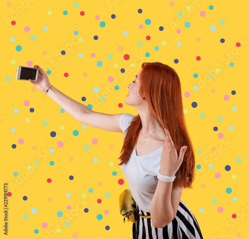 Lovely selfie. Beautiful young girl smiling and gently touching her hair while taking selfies