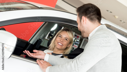 Woman buying a car in dealership sitting in her new auto