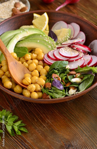 Vegetarian bowl with chickpeas, radish, avocado, herb and seeds, salad, vertical