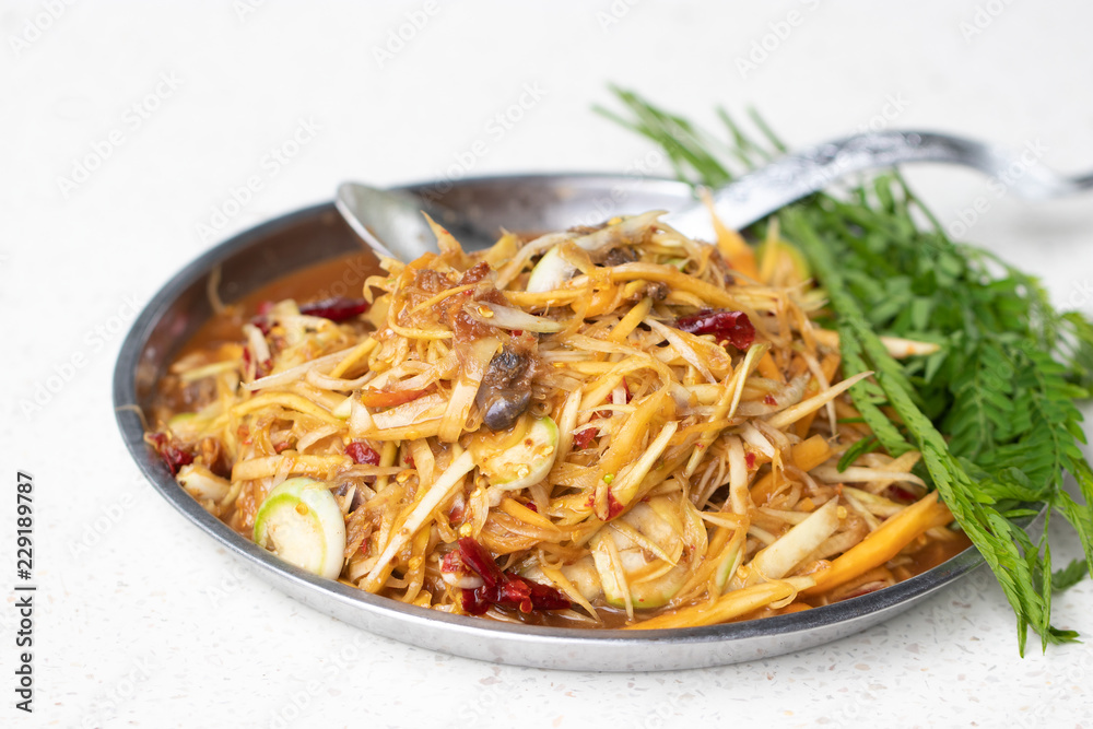 Papaya salad with pickled fish and many herbs in silver tray. Street foods found in Thailand and general restaurants. It has a delicious and spicy taste. Soft focus and blur.
