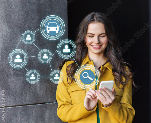 car sharing, modern technology and people concept - smiling teenage girl with smartphone on city street photo