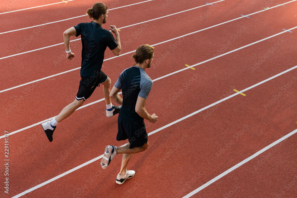 Two twins sportsmen brothers running at the stadium outdoors.