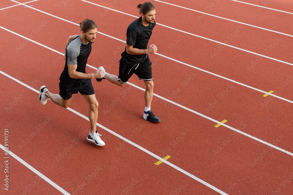 Two twins sportsmen brothers running at the stadium outdoors.