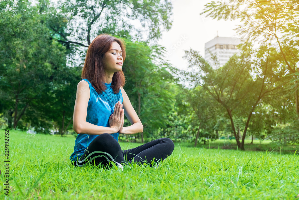 young and beautiful asian woman practicing yoga outdoors in park with green nature background. lifestyle concept.