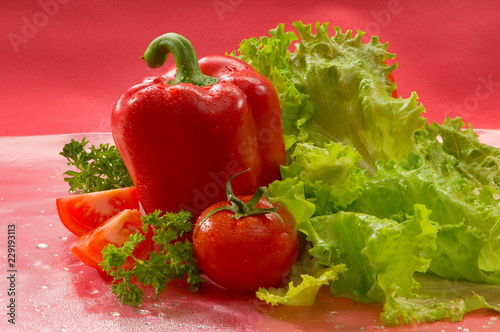 Овощи - помидоры, перец, салат, на красном фоне Vegetables - tomatoes, peppers, lettuce on a red background