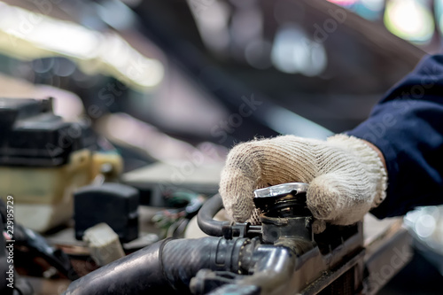 Car mechanic are opening the radiator cap. Check to see if the water level reaches the threshold.