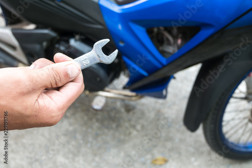 People are repairing a motorcycle Use a wrench and a screwdriver to work. Use the wrench to tighten the cylinder.