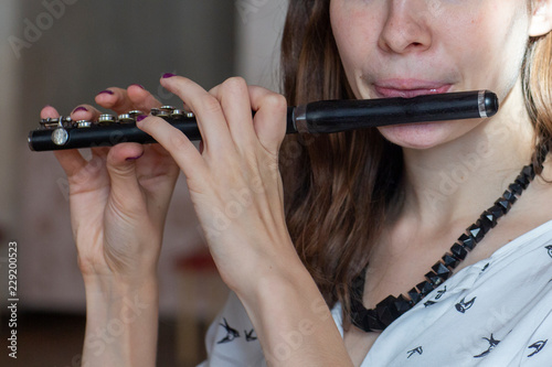 A gorgeous young woman sitting and playing the flute piccolo photo