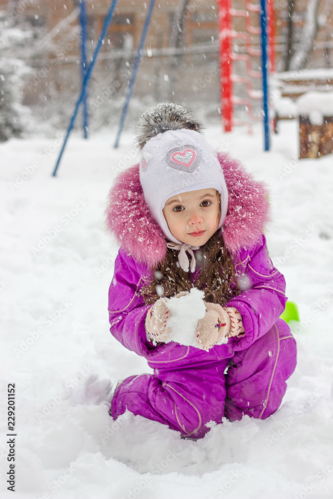 Little kid girl playing snowballs on winter morning.