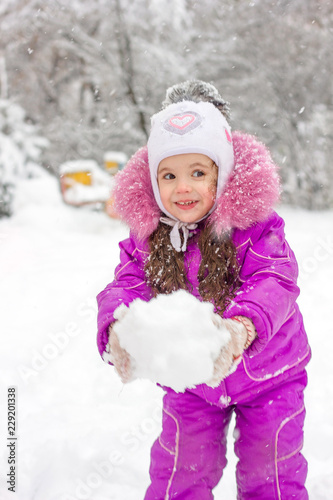 Little kid girl builds snow...