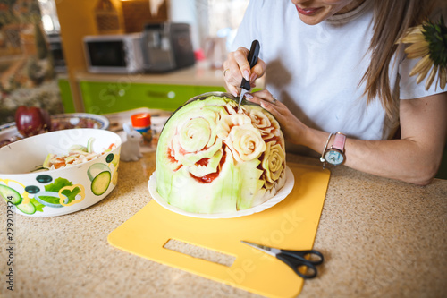 A young girl carving watermelon in her beautiful kitchen. Photo hobby
