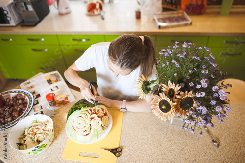 A young girl carving watermelon in her beautiful kitchen. Photo hobby