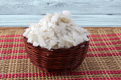 uncooked puffed rice flakes poha in basket for indian gujarati traditional breakfast snack  photo