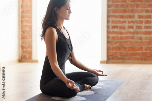 Slender asian yoga girl sitting in Lotus pose close up